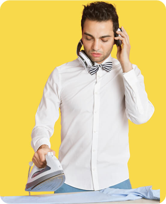 Dressed-up man ironing a shirt and holding his headphones